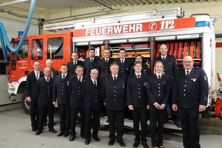 Zahlreiche geehrte oder beförderte Feuerwehrmitglieder stehen vor einem Löschfahrzeug des Löschzuges St. Vit