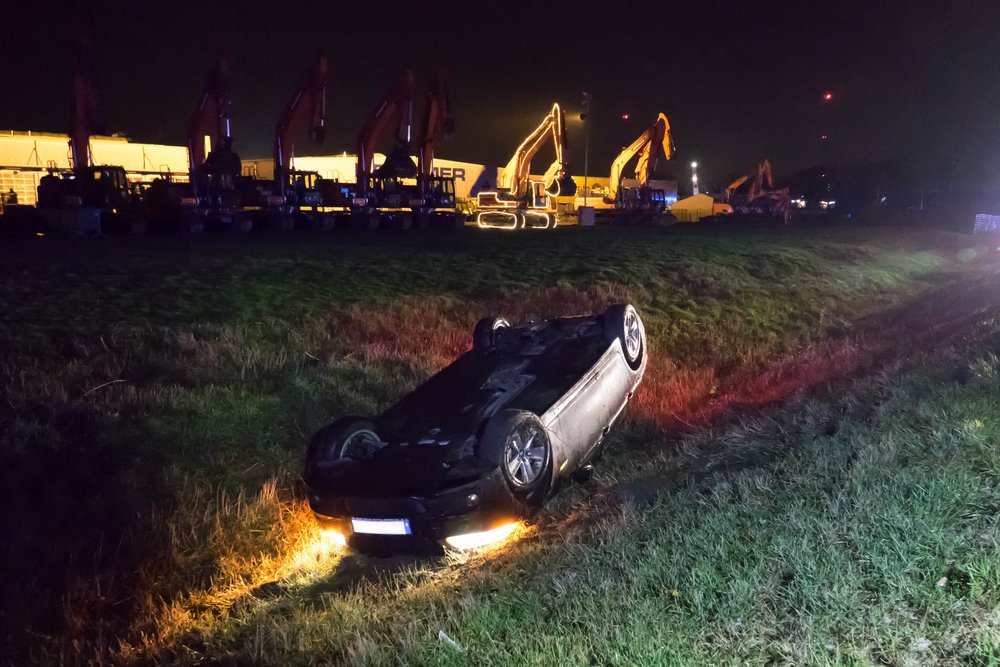 Ein PKW liegt nach einem Verkehrsunfall kopfüber in einem Graben.